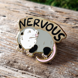 enamel pin of an opossum with the word "nervous" above it