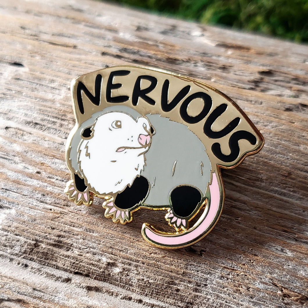 enamel pin of an opossum with the word 